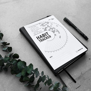 Filled in habit tracker printable laying on a black notebook
